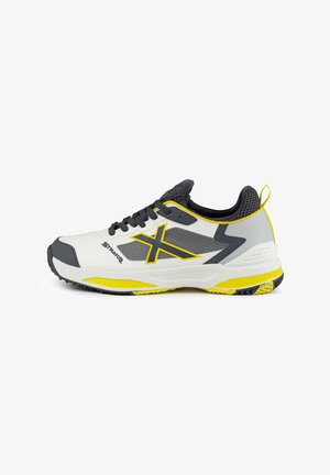 Sportliche Schuhe mit einem weißen synthetischen Obermaterial, grauen und gelben Akzenten, Netzdetails und einer strukturierten Sohle für Grip.