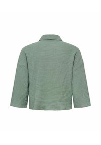 Giacca verde corta realizzata in tessuto testurizzato. Presenta un collo e maniche ampie. La parte posteriore mostra un sottile motivo trapuntato.
