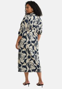 Bloemenprint jurk in marineblauw en crème, met een vergrendelde taille, driekwart mouwen en een vloeiende A-lijn silhoutte.