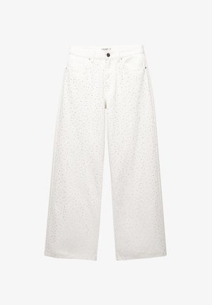 Jeans albe din denim cu croiala largă, având un model uniform de puncte negre mici, cinci buzunare și închidere cu buton metalic.