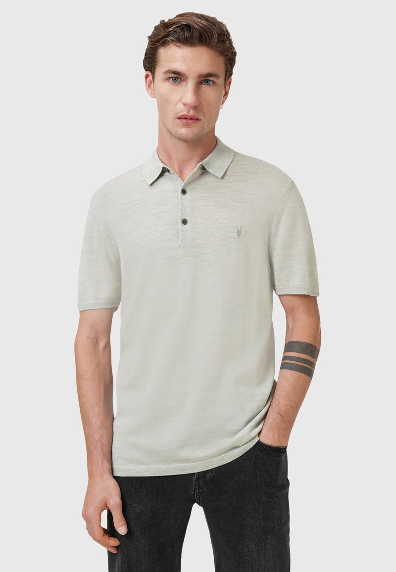 Lys grøn polo t-shirt med korte ærmer, tre-knaps lukning, subtil tekstur og et lille logo på brystet. Båret sammen med mørke jeans.