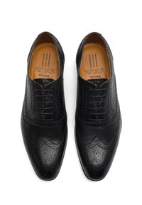 Chaussures formelles en cuir noir avec un design brogue, présentant des détails perforés et un bout pointu. L'intérieur a un marquage en tan.