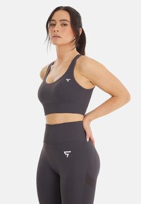 Grijze sportbeha met een geribbelde textuur en brede banden, gecombineerd met hooggetailleerde bijpassende leggings met een logo aan de linkerkant.