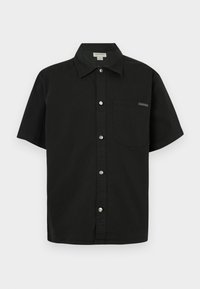 Črna majica s kratkimi rokavi iz bombaža, z gumbastim zapenjanjem spredaj, enim žepom na prsih in majhnim logotipom ob žepu.