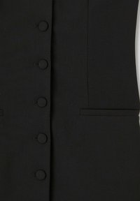 Gilet noir ajusté avec six boutons ronds recouverts de tissu, poches latérales et un design élégant et structuré avec une texture mate.