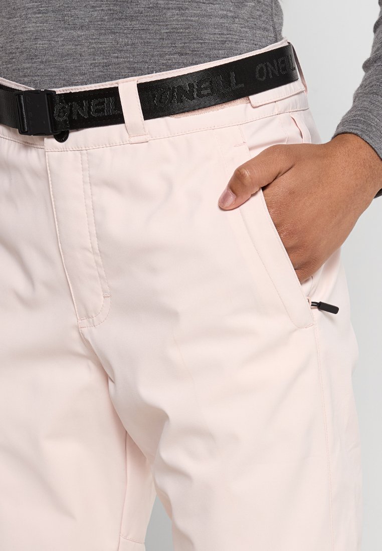 Jasnoróżowe spodnie snowboardowe mają czarny regulowany pasek z nazwą marki "O'Neill", boczną kieszeń na zamek i gładką teksturę.