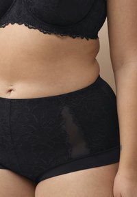 Schwarze Spitzen-Hipster-Shorts mit transparenten Einsätzen, floralen Mustern und einem glatten Bund. Weicher Stoff mit kontrastierenden Designelementen.
