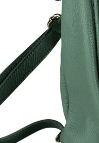 Groene, gestructureerde leren schouderriem bevestigd aan metalen ringen op een bijpassende groene leren tas.