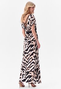 Robe maxi noire et rose blush avec imprimé zèbre, présentant un dos nu et des bretelles croisées, une taille cintrée et une jupe fluide.