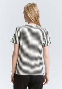 T-shirt rayé en noir et blanc, à manches courtes, coupe décontractée, en coton doux, col rond, avec un design épuré et simple.