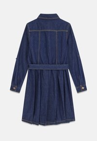 Mörkblå denimklänning med långa ärmar, midjebälte, veckad kjol och knappade manschetter, visad bakifrån mot en vit bakgrund.