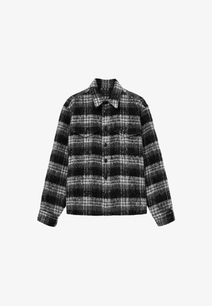 Veste en flanelle à carreaux dans des tons de noir et de gris, dotée de deux poches poitrine, fermeture à boutons et col classique.