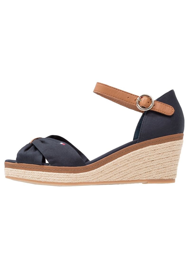 Sandale compensée bleu marine avec sangle de cheville beige et boucle, tissu noué à l'avant, et semelle plateforme en jute tressé.