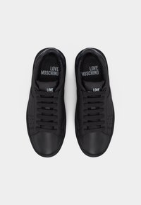 Ζευγάρι μαύρα αθλητικά παπούτσια Love Moschino με κορδόνια, φωτογραφημένα από πάνω σε απλό ανοιχτόχρωμο φόντο.