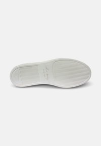 Suela de goma blanca con un patrón texturizado, que presenta líneas en zigzag y un detalle de marca. Acabado suave con un borde redondeado.