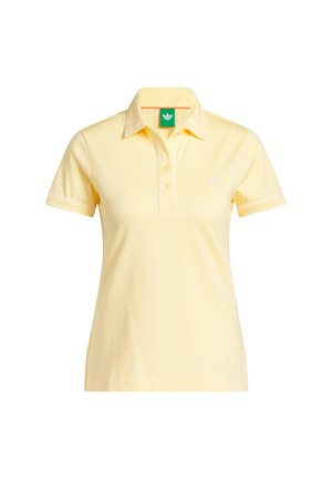 Žlté polo tričko s krátkym rukávom, tromi gombíkmi, golierom, malým logom Adidas na hrudi a zelenou štítkou vo vnútri goliera.