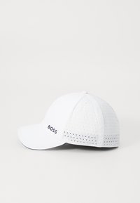 Fehér baseball sapka perforált oldalakkal és ívelt vizsgálgákkal. Az elülső bal oldalán egy sötét "BOSS" logó található.