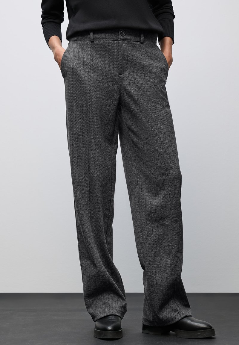 Los pantalones grises con patrón presentan un diseño de espiga, una cintura alta y dos bolsillos laterales. La tela tiene una textura suave y un corte holgado.