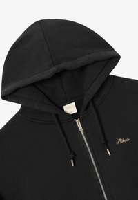 Juodas zip-up džemperis iš minkštos medžiagos, su ryšimo kapišonu, auksiniu siuvinėjimu su užrašu "Blkvrs" ir sidabro spalvos užtrauktuku.