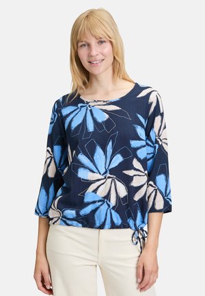 Blusenoberteil mit blauen und weißen Blumenmotiven auf navyfarbenem Hintergrund, mit Dreiviertelärmeln und einem gerafften Bindedetail in der Taille.