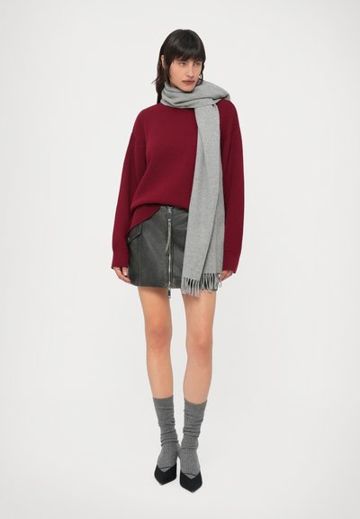 Camisola borgonha, cachecol cinzento, saia preta de couro com fecho éclair, meias cinzentas até ao joelho e sapatos pretos com salto. Design simples, texturas suaves.