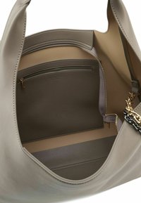 Grijze leren draagtas met een ruime beige binnenkant, voorzien van een ritssluitingvak en een verstelbare riem. Met gouden metalen accenten.