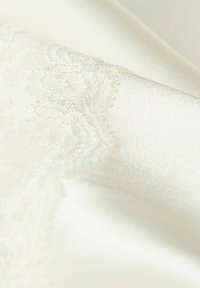 Crème satijnen stof met een zachte textuur, voorzien van een delicate kantpatroon langs één rand. Gladde oppervlakte met subtiele glans.