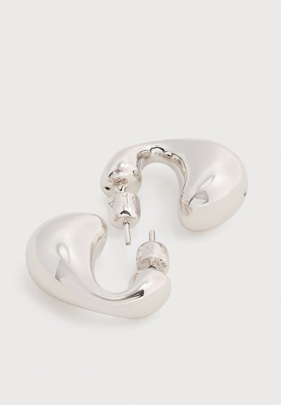 Ζευγάρι λαμπερών, λείων, καμπυλωτών ασημένιων κρίκων με καρφίτσα και κούμπωμα πεταλούδας σε λευκό φόντο.