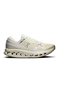 Chaussure de sport beige clair avec une tige en maille, des accents blancs et une semelle distinctive rembourrée présentant des découpes pour le soutien et la flexibilité.