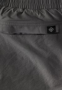 Donkere grijze stoffen short met een gestructureerd patroon, elastische tailleband en een klein zwart merkembleem op het achterzakje.