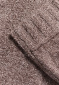 Brązowy sweter z dzianiny o miękkiej, puszystej fakturze z żebrowanym wykończeniem mankietów, prezentujący mieszankę grubego i cienkiego przędzy.