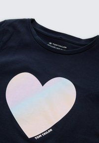 Navyfarbendes T-Shirt mit einem großen, schillernden Herzensdesign auf der Vorderseite, einem Rundhalsausschnitt und dem "TOM TAILOR"-Logo am unteren Rand.