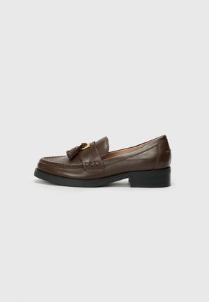 Brown leather loafers with a decorative tassel and gold-toned hardware, featuring a low block heel and detailed stitching on the upper.