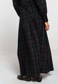 Robe longue à carreaux présentant des teintes de vert foncé, de marine et de bourgogne. Fabriquée en tissu texturé avec une jupe plissée et des manches boutonnées.