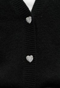 Μαύρη πλεκτή ζακέτα με ριμπ γιακά και δύο κουμπιά σε σχήμα καρδιάς με στρας που κλείνουν το μπροστινό μέρος.