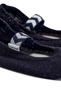 Mörkblå glittriga baletttofflor med elastiska remmar med zigzag-mönster och "hummel"-loggor mot en vit bakgrund.