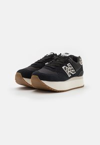 Scarpe da atletica nere con tomaia in suede e mesh, dotate di intersuola bianca, suola in gomma naturale e un accento a motivo sul tallone.