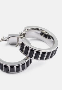 Sølv hoop øreringer med rektangulære svarte aksentstein innlagt i en teksturert ring. Designet er elegant og moderne.