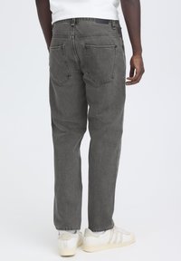 Blugi gri din denim, cu croială dreaptă, având buzunare spate și un finisaj curat. Asortați cu adidași albi și un tricou simplu.