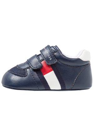 Chaussures en cuir bleu marine pour garçons avec des accents blancs et rouges, dotées d'une sangle en velcro et d'un design à bout rond. Motif texturé sur la tige.