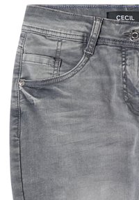 Jean en denim gris en gros plan montrant la poche avant, le passant de ceinture, le bouton métallique, le rivet et l'étiquette de marque noire "CECIL" sur la ceinture.