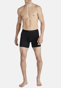 Svarta atletiska boxerkalsonger med en slät textur, elastisk midjeresår och formad påse, gjorda av andningsbart material. Inga mönster eller detaljer.