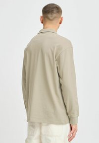 Lange mouw polo shirt in licht beige, met een ontspannen pasvorm, zachte stof en een subtiele textuur, met een klassieke kraag en ribgebreide manchetten.