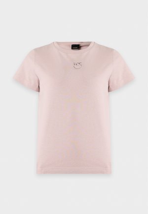 Femme portant un t-shirt rose clair à manches courtes et une jupe midi en cuir marron foncé avec une fente à l'avant et des escarpins bordeaux.