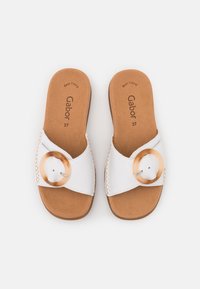Sandali bianchi slip-on realizzati in materiale sintetico, con un grande accento circolare color sabbia, dettagli intrecciati e una soletta imbottita color sabbia.
