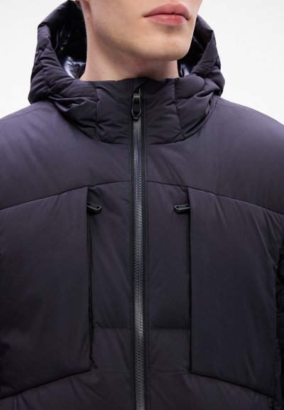 Veste rembourrée noire avec un col haut et une capuche. Présente une fermeture éclair verticale et deux poches avant avec des cordons ajustables. Texture de tissu lisse.