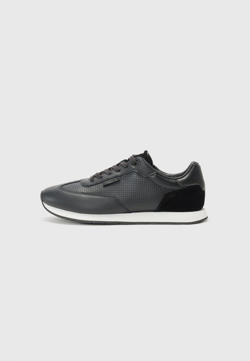 Zwarte sport sneakers met een leren bovenwerk, perforaties, suède accenten en een witte rubberen zool. Klassiek vetersluiting ontwerp.