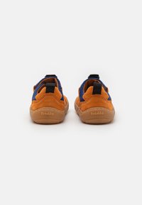 Vue arrière de chaussures avec un dessus en suède orange et textile bleu, avec des languettes noires et des semelles en caoutchouc beige, logo en relief sur le talon.
