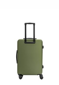 Groene harde koffer met zwarte telescopische handgreep uitgeschoven en vier spinnerwielen op een witte achtergrond.