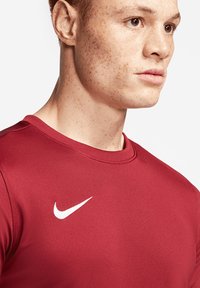 Nike rode sportshirt met een ronde halslijn. Bevat een wit swoosh-logo op de borst. Gladde, lichte en aansluitende stof.